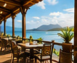 Terraza con mesas frente a un paisaje tropical · Imagen ilustrativa generada con IA